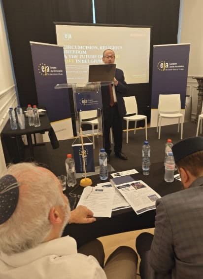 Spreker geeft presentatie over religieuze besnijdenis en standaarden.