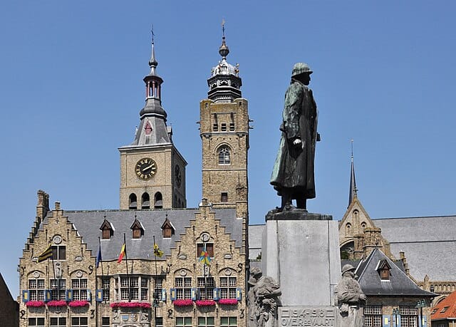 Stadplein in Diksmuide met standbeeld en historische gebouwen.