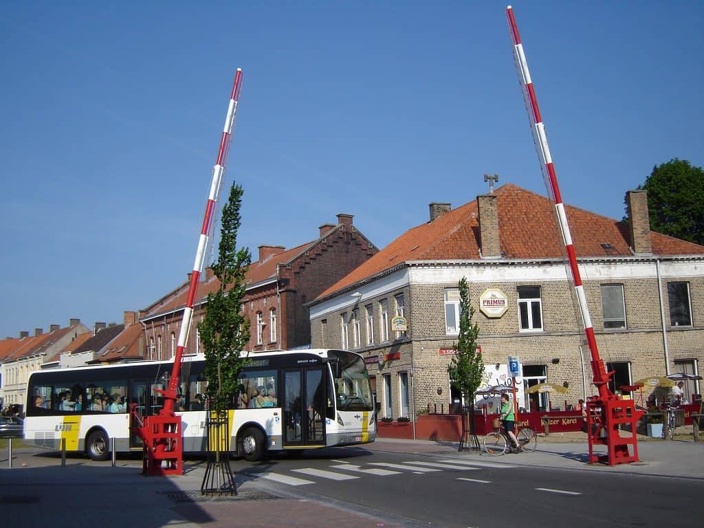 Bus stopt bij overweg met slagbomen in Kouter, België.