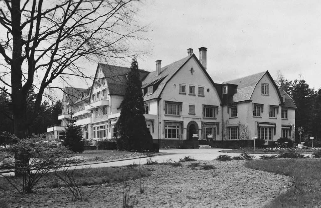 Historisch gebouw met grote tuin en bomen, mogelijk een landhuis of hotel.