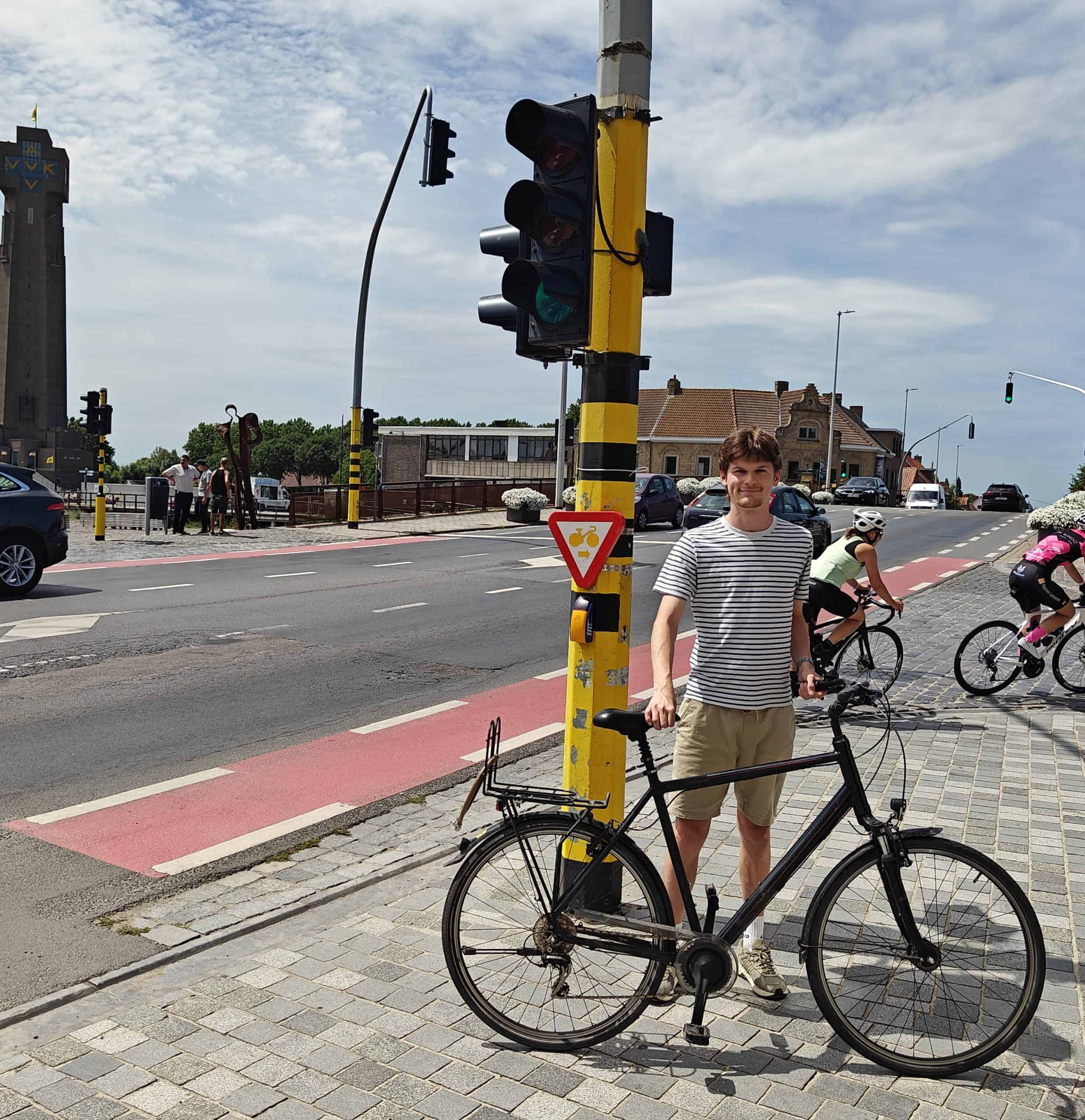 Fietser wacht bij verkeerslicht met fiets onder gele en zwarte paal.
