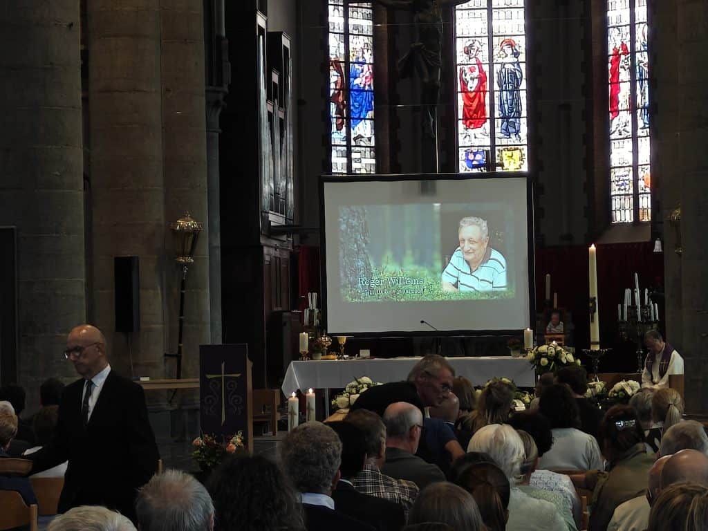 Herdenking in de kerk met een video van Roger Willems op het scherm.