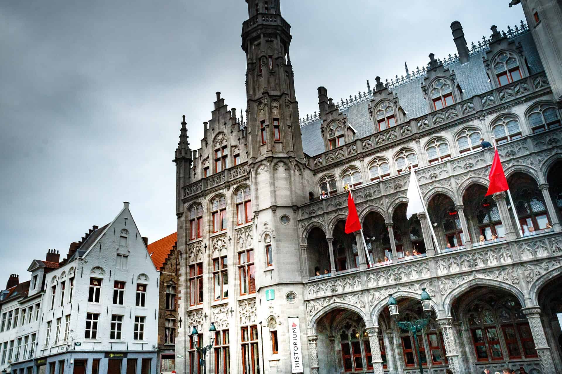 Gothisch gebouw in Brussel met rode vlaggen en torentjes.