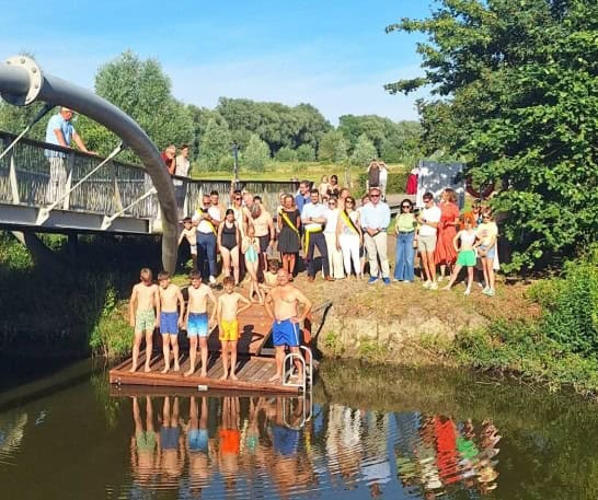 Kinderen springen van de steiger in het water tijdens een zomers evenement.