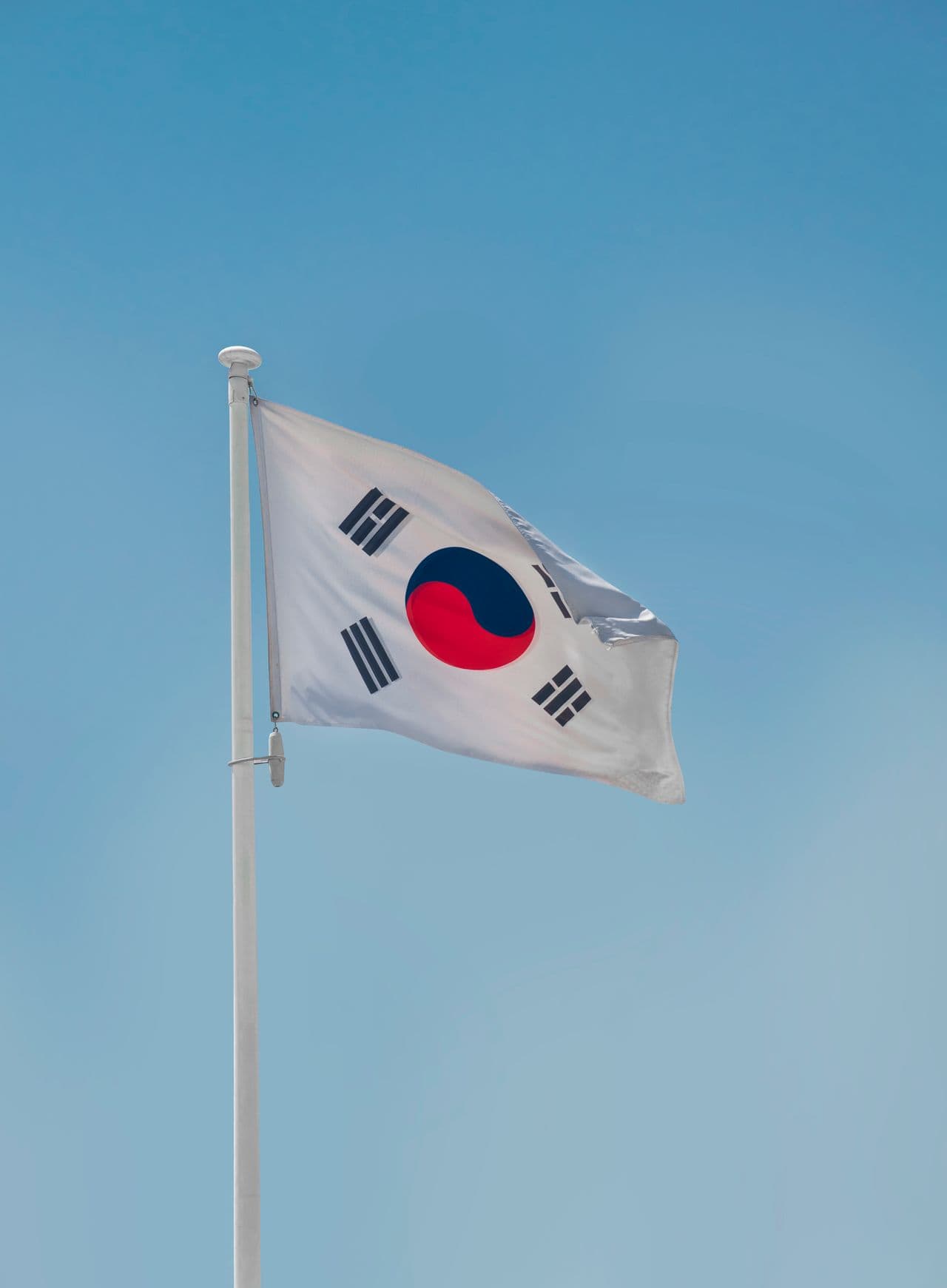 Zuid-Koreaanse vlag wappert in de wind tegen een blauwe hemel.