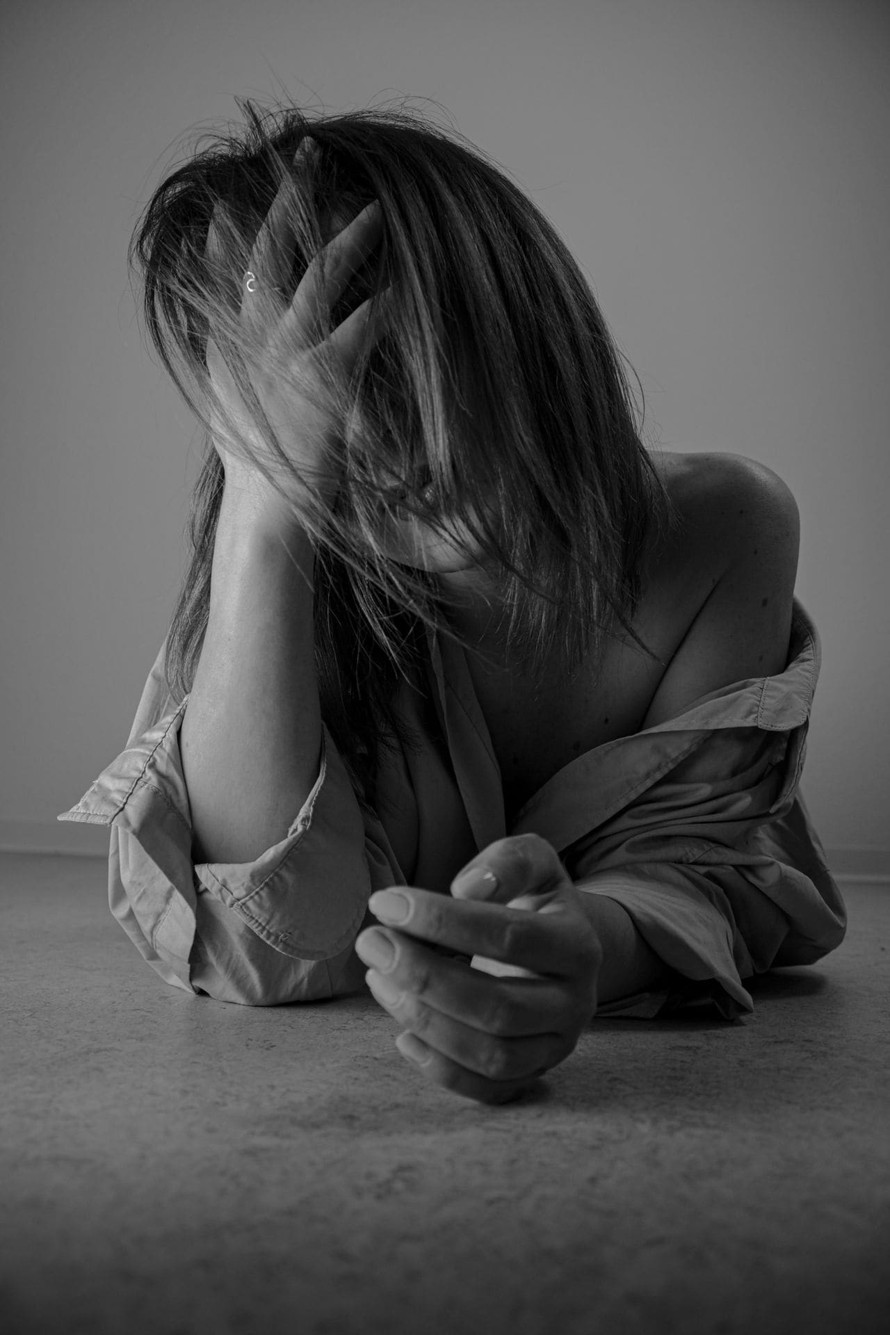 Vrouw met hand in haar haar, zichtbaar emotioneel in zwart-wit.