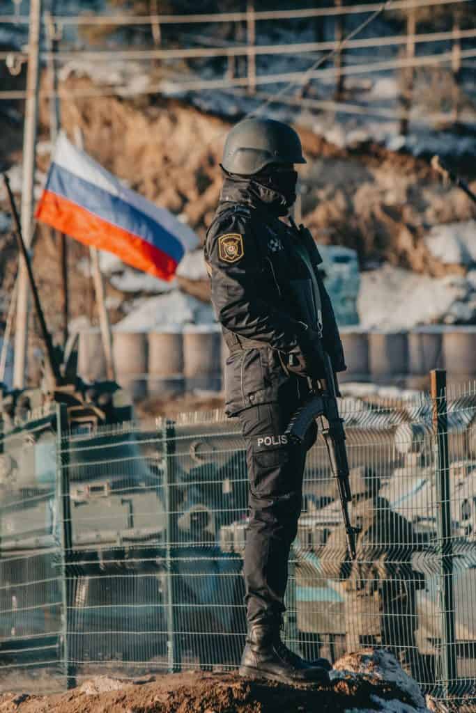 Politieagent in beschermende uitrusting met Russische vlag op achtergrond.